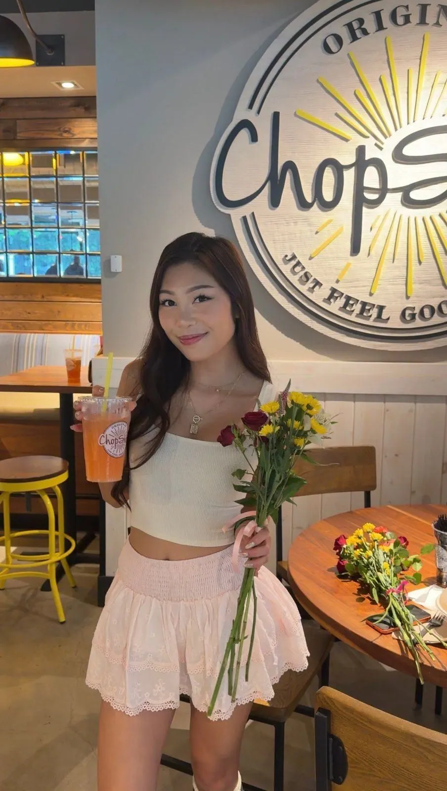 Creator holding a bouquet and a juice beneath the Original ChopShop sign