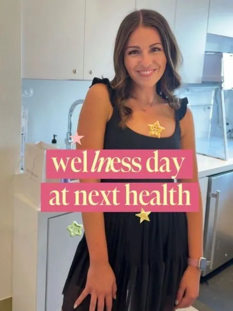 Smiling creator in a black dress with the caption wellness day at Next Health
