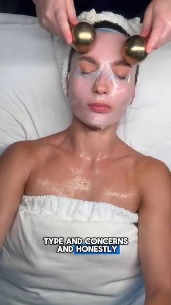 Woman receiving a facial with a sheet mask and gold cooling globes