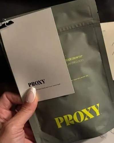 Hand holding a Proxy Wellness supplement pouch and product card