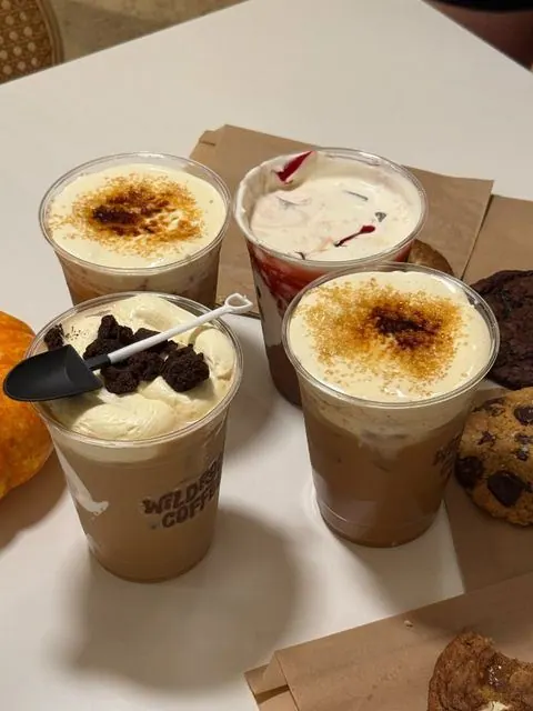 Iced lattes topped with cream and cookies on a café table