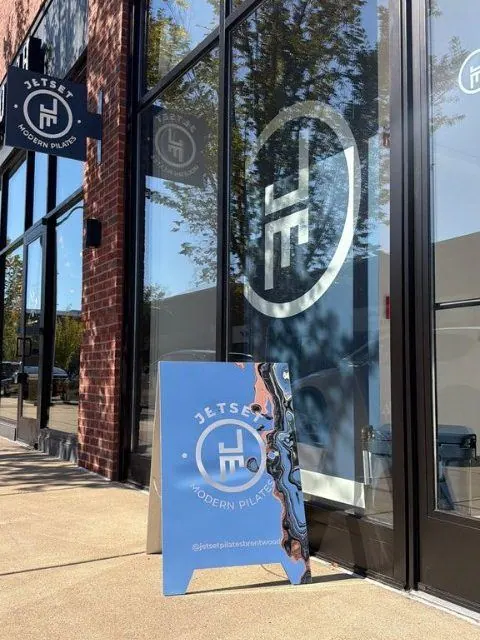 JETSET Pilates storefront with its logo on the glass and a blue sidewalk sign