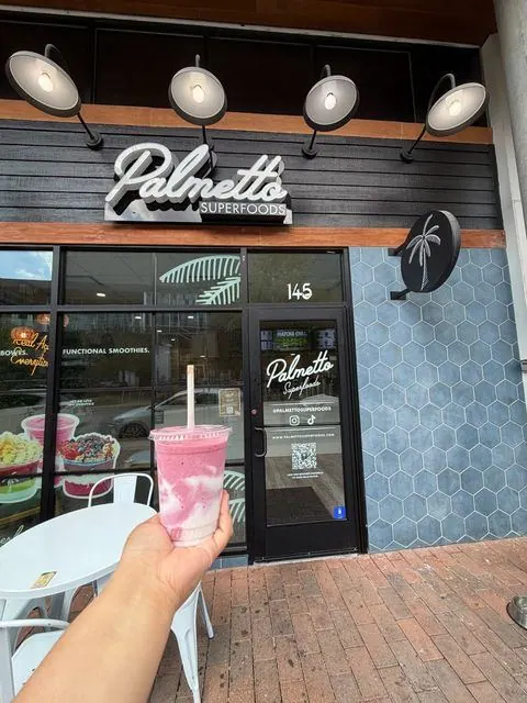 Pink smoothie held up in front of the Palmetto Superfoods storefront